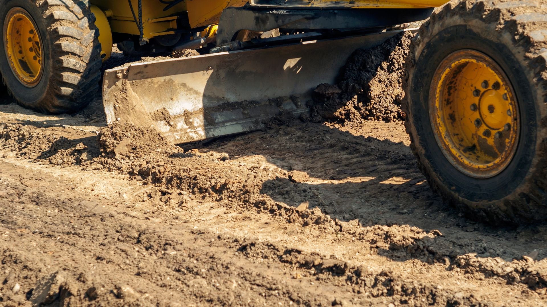 Yellow construction grader moving dirt on a construction site