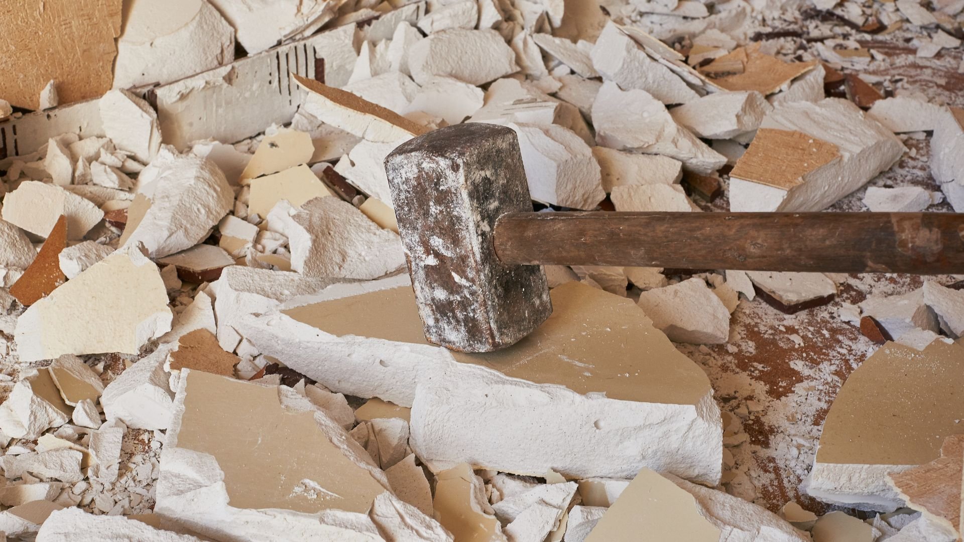 Sledgehammer on broken drywall and debris during renovation or demolition